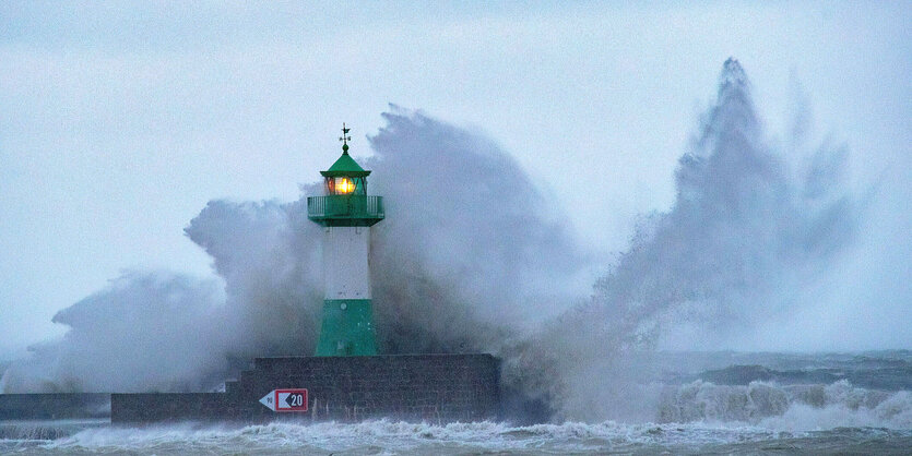 Wellen brechen gegen einen Leuchtturm in der Dämmerung