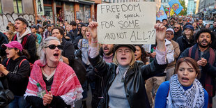 Demonstratinnen mit einem Plakat "Freedom of speech for some and not all?"