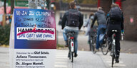 Radfahrer radeln an einem beschmierten Werbeplakat für Olympische Spiele 2024 in Hamburg vorbei