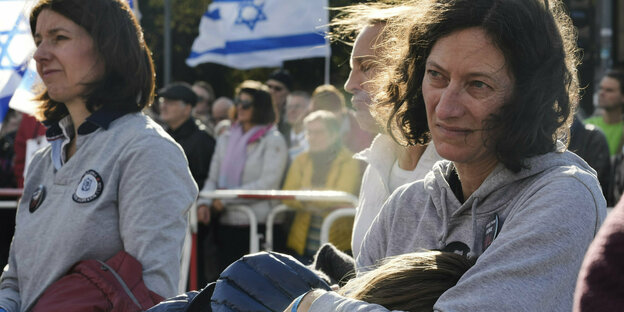 Zwei Frauen bei der Kundgebung am Brandenburger Tor. Eine Frau hält ein Kind im Arm, dahinter ist eine israelische Flagge zu sehen