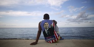 Ein Kubaner mit einem Obama-T-Shirt sitzt am Meer