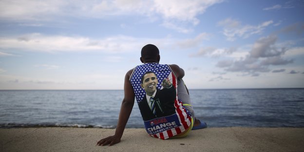 Ein Kubaner mit einem Obama-T-Shirt sitzt am Meer
