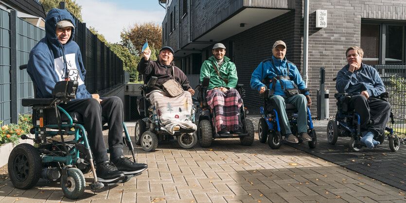 Fünf Männer in Rollstühlen sitzen in der Sonne