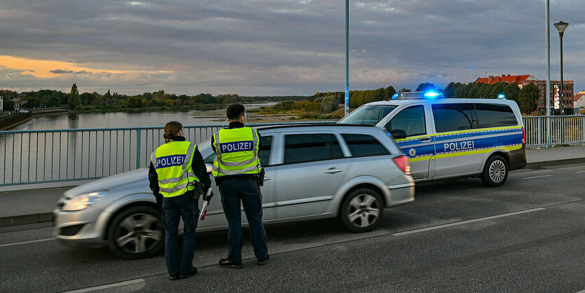 Ein Bundespolzist und eine Bundespolizistin kontrollieren ein Auto