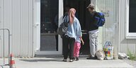 Menschen mit Reisetaschen stehen an der Tür eines Ankunftszentrum in München
