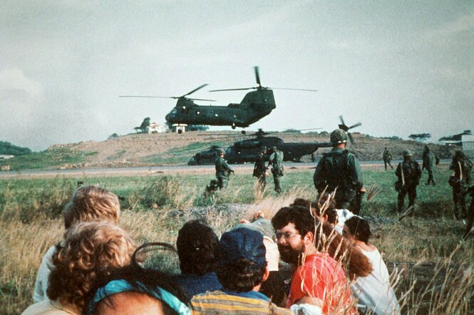 Menschen auf einem freien Feld vor einem amerikanischen Militärhubschrauber