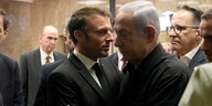 Frankreichs Präsident Macron umarmt den Ministerpräsidenten Netanjahu mit ernster Miene