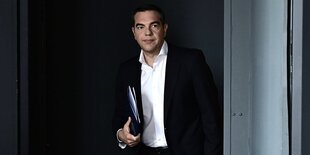 Alexis Tsipras mit weißem Hemd, schwarzem Sakko und Aktenmappe