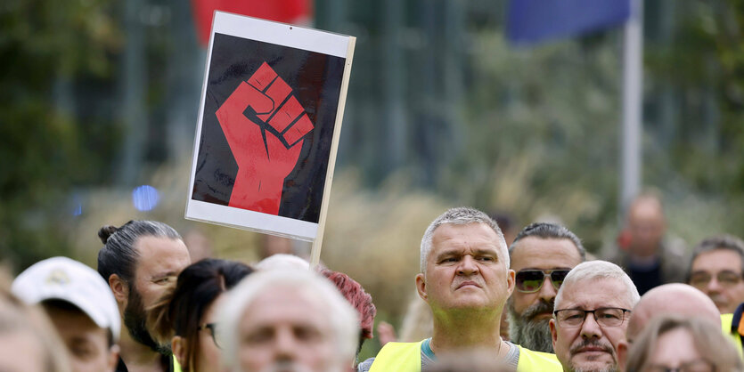 Proteste vor dem Meven Dumont Haus in Köln mit einer Faust auf einem Plakat