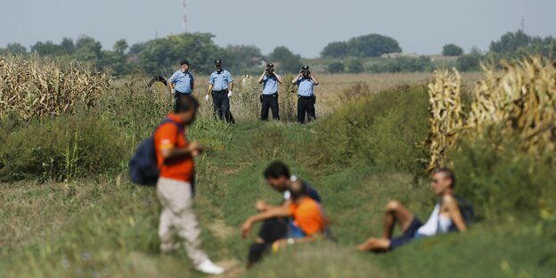 Kroatische Polizisten beobachten Flüchtlinge an der Grenze zu Serbien.