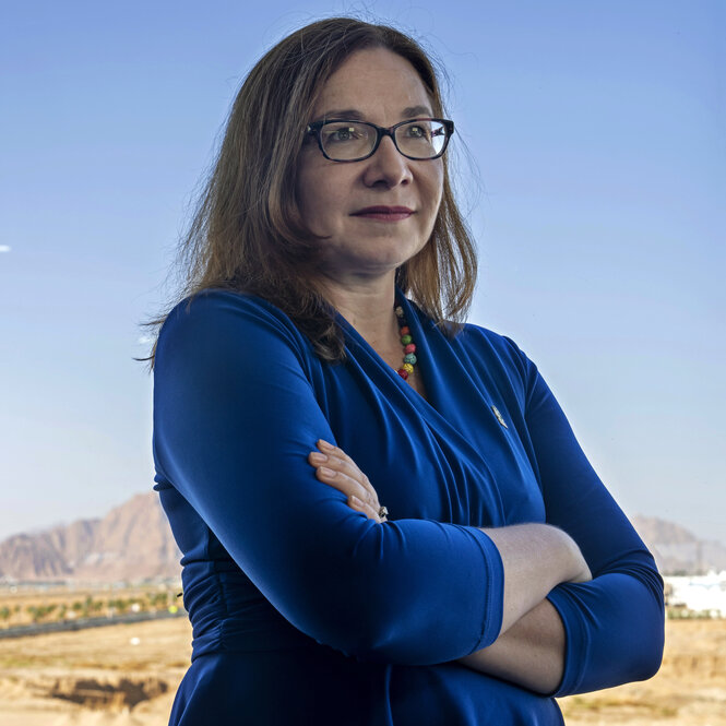 Katharine Hayhoe mit einem blauen Kleid vor einer Berglandschaft