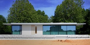 ein flaches weißes Gebäude am Strand, die Fenster sind zugezogen