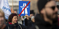 eine Frau hält ein Schild: Autobahnzeichen durchgestrichen bei ener Kundgebung