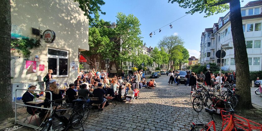 Eine Straßenecke im Bremer Viertel. Links sieht man die Kneipe "Horner Eck" und Menschen, die davor sitzen