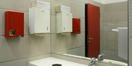 Ein roter Tampon- und Bindenspender neben dem Handtuchspender hängt in einer Damentoilette an der Wand beim Waschbecken