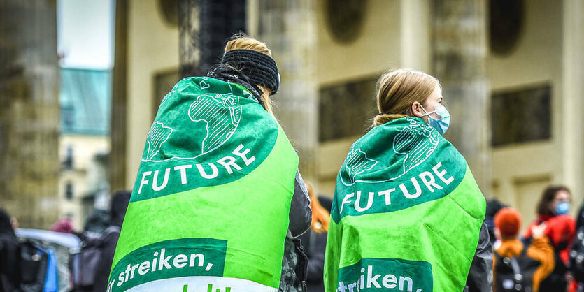 Aktivist:innen von Fridays for Future tragen Fahne als Umhang