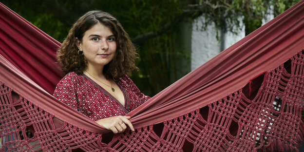 Eine junge Frau in einer roten Hängematte schaut in die Kamera: Autorin Özge Inan aus Berlin