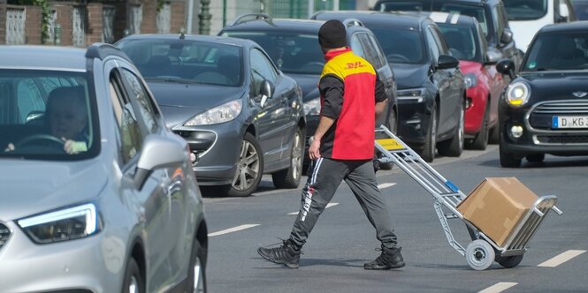 Ein Paketzusteller überquert eine stark befahrene Straße