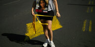 Eine Frau läuft auf einer Straße, umgehängt ein Schild: "Bring her home Now!"