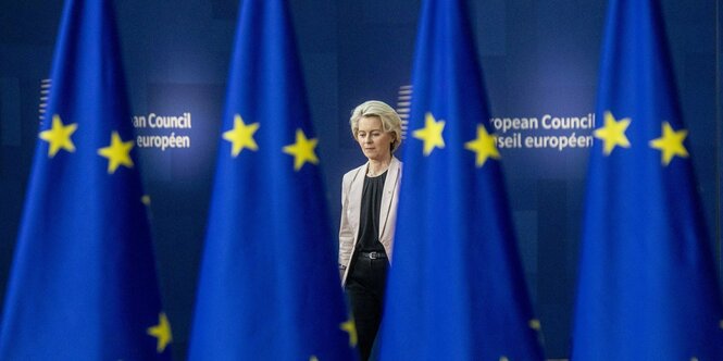 Ursula von der Leyen, Präsidentin der Europäischen Kommission hinter EU-Fahnen