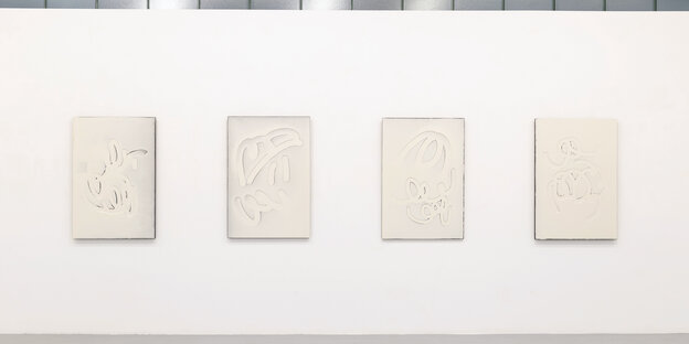 vier abstrake grafische Arbeiten, weiß auf weiß, hängen nebeneinander an einer Wand