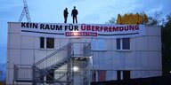 Zwei Rechtsextreme stehen in Dresden auf dem Dach einer geplanten Asylunterkunft. Mit einem Banner fordern sie "Kein Raum für Überfremdung"