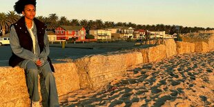 Die Moderatorin Aminata Belli sitzt am Strand in Namibia