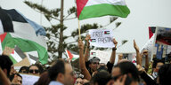 Protest in Tunis mit palästinensischen Flaggen - ein junger Mann mit Palästinensertuch auf dem Kopf hält eine Schild hoch: Free Palestine