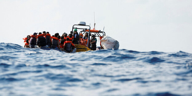 Menschen in Rettungswesten in einem überfüllten Boot