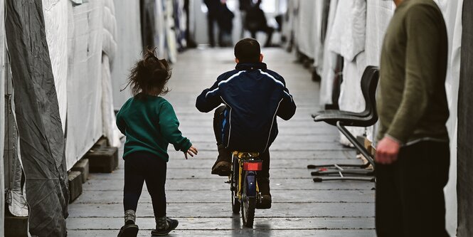 Kinder sind auf dem Flur einer Zeltunterbringung unterwegs.