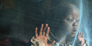Ein Kind aus Nairobi hinter einem Moskitonetz