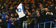 Fußballfans feiern mit israelischer Fahne auf einer Tribühne