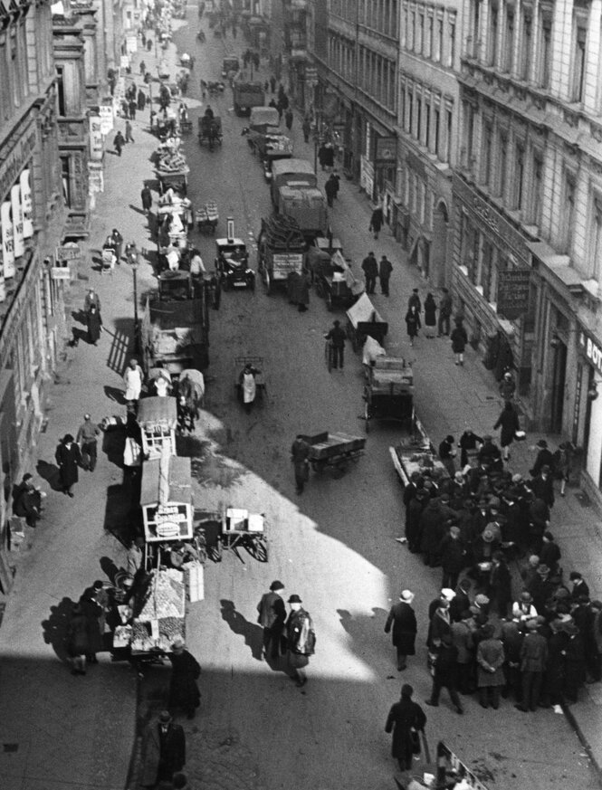 historische Aufnahme, Blick in eine belebte kleine Straße mit vielen Menschen und Autos