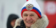 Ein alter Mann trägt eine weiße Mütze mit russischem blau-rotem Logo