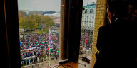 Blick aus einem Fenster hinab auf eine mit Palestina-Fahnen demonstrierende Menschenmenge