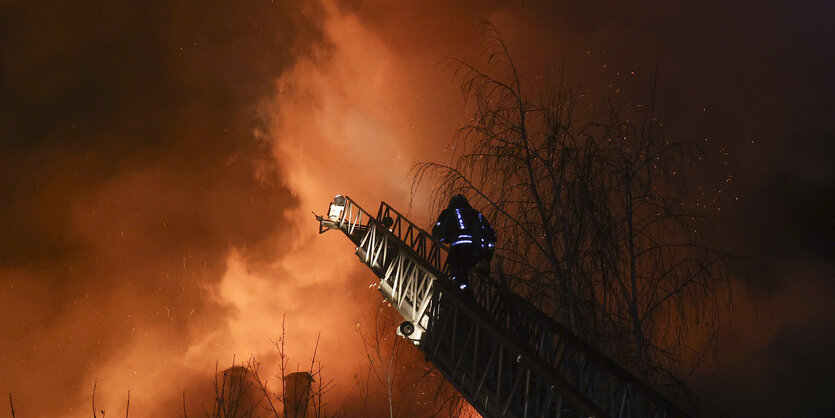 Eine Feuerwehrmann vor Rauchwolken in der Nacht