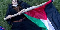 Eine Frau liegt mit einer palästinensischen Fahne auf dem Boden