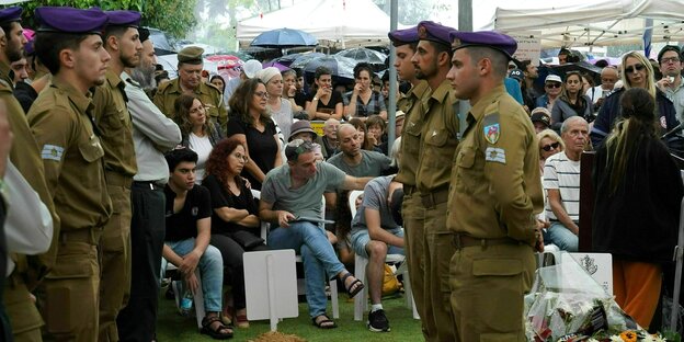 Junge Soldaten in Uniform stehen seitlich am Grab von Lavi lipschitz , seine Eltern und Geschwister sitzen auf Stühlen, Freunde und Verwandte stehen an der Stirmseite