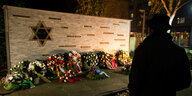 Ein Mann steht am 09.11.2016 nach einer Gedenkveranstaltung der Jüdischen Gemeinde zu Berlin an die Pogrome vom 9. November 1938 im Jüdischen Gemeindehaus in Berlin vor einer Gedenkmauer, auf der die Namen von Konzentrationslagern sowie von Ghettos stehe