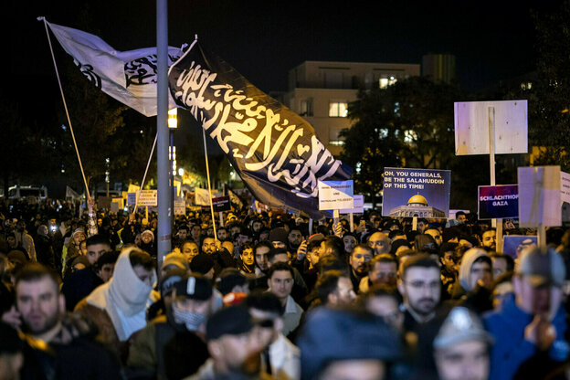 Protestzug von vorwiegend jungen Männern und einer großen Flagge mit arabischer Schrift