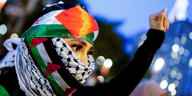 Eine mit einer Fahne der Palestinenser vermummte Person