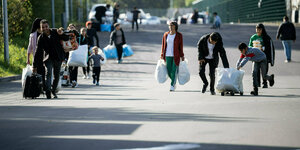Menschen mit Gepäck gehn auf einer Straße
