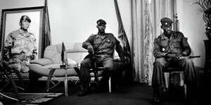 Zwei Soldaten sitzen auf Stühlen vor einem Portraitbild