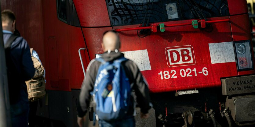 Personen gehen auf dem Bahnsteig auf einen Regionalzug zu