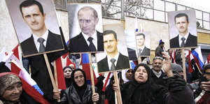 Syrische Frauen demonstrieren mit Bildern von Assad und Putin.