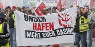 Hafenarbeiter demonstrieren mit einem Transparent: "Unser Hafen - nicht Euer Casino"