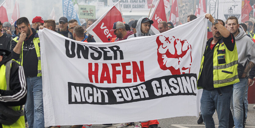 Hafenarbeiter demonstrieren mit einem Transparent: "Unser Hafen - nicht Euer Casino"