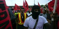 Demonstranten mit Gesichtsmaske und roten Fahnen in Panama City