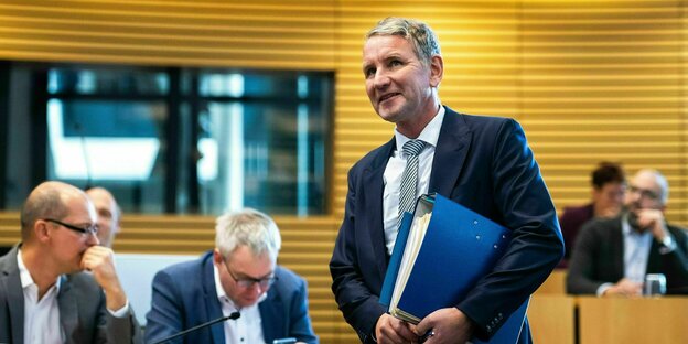 Björn Höcke mit einem Aktenordner in der Hand geht an seinen Kollegen im Thüringer Landtag vorbei