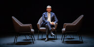 Michel Friedman sitzt auf einem Sessel zwischen zwei leeren Sesseln